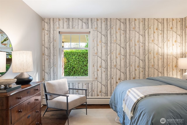 bedroom featuring baseboard heating, wood finished floors, and wallpapered walls