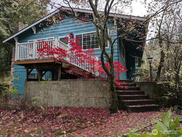 rear view of property featuring stairway and a wooden deck