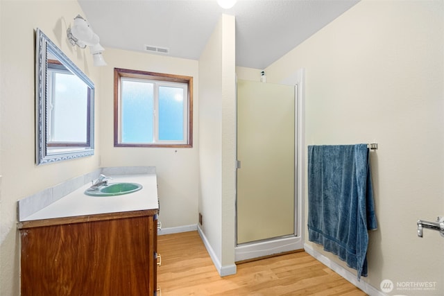 full bathroom with a stall shower, baseboards, visible vents, wood finished floors, and vanity