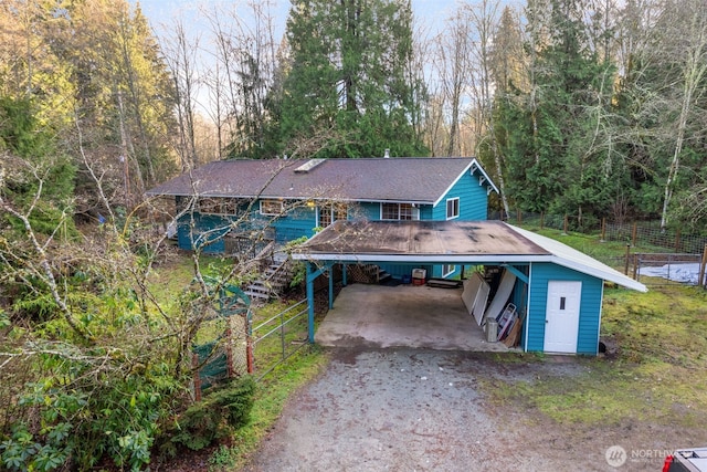 view of front of property featuring a carport, driveway, stairway, and fence