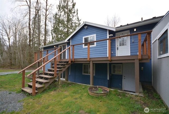 rear view of house featuring stairway, a yard, and a wooden deck