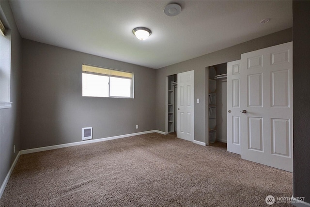 unfurnished bedroom featuring visible vents, baseboards, carpet, and multiple closets