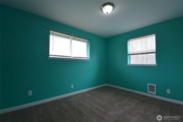 empty room featuring visible vents, dark carpet, and baseboards