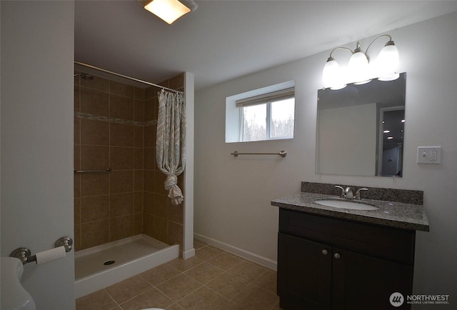 full bath featuring vanity, tile patterned flooring, baseboards, and a tile shower