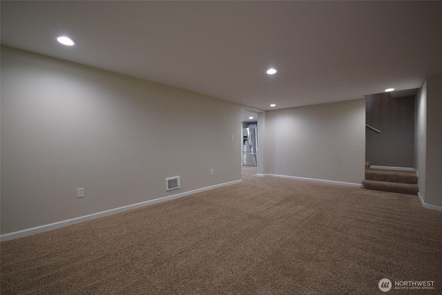 finished basement featuring stairway, recessed lighting, visible vents, and stainless steel fridge