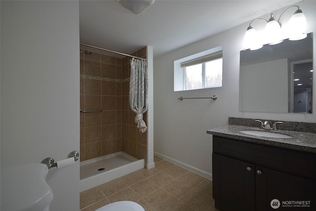 bathroom with a tile shower, tile patterned floors, vanity, and baseboards