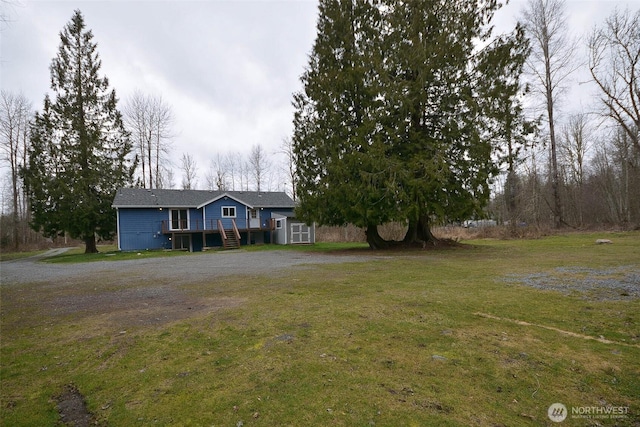 ranch-style home with a front yard, driveway, and a wooden deck