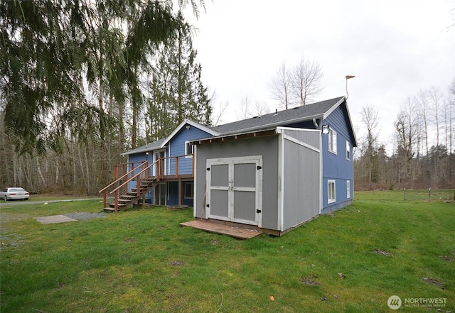 rear view of house with a wooden deck, an outdoor structure, stairs, and a yard