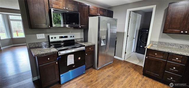 kitchen with light stone counters, wood finished floors, stainless steel appliances, dark brown cabinetry, and washer / dryer