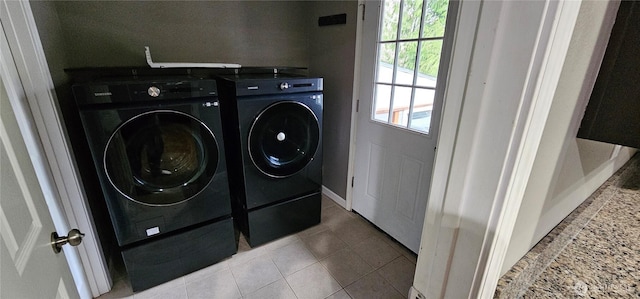 laundry area with washer and clothes dryer, light tile patterned floors, and laundry area