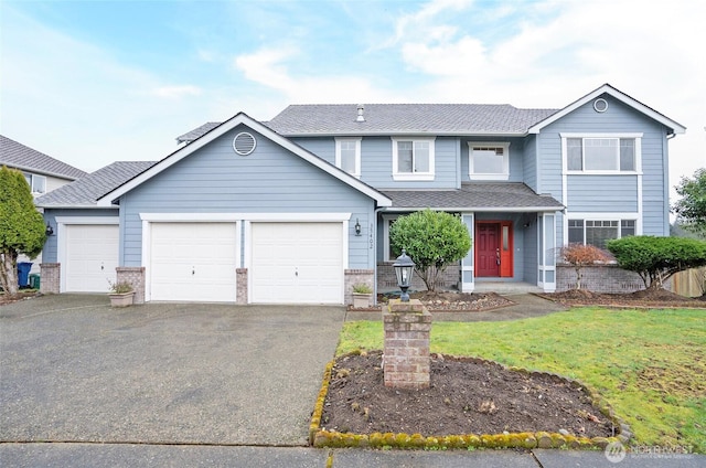 traditional-style home featuring a garage, driveway, a shingled roof, and a front lawn