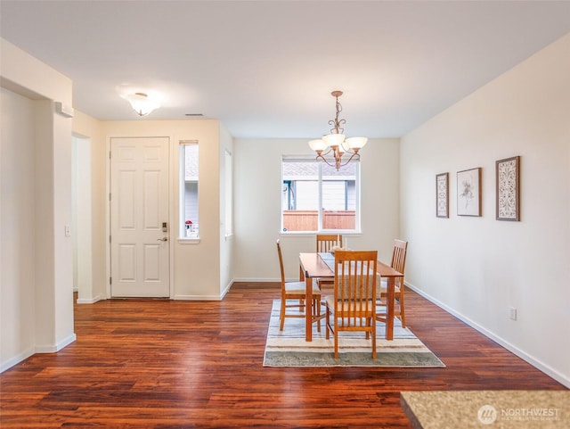 dining space featuring baseboards, dark wood finished floors, and a notable chandelier