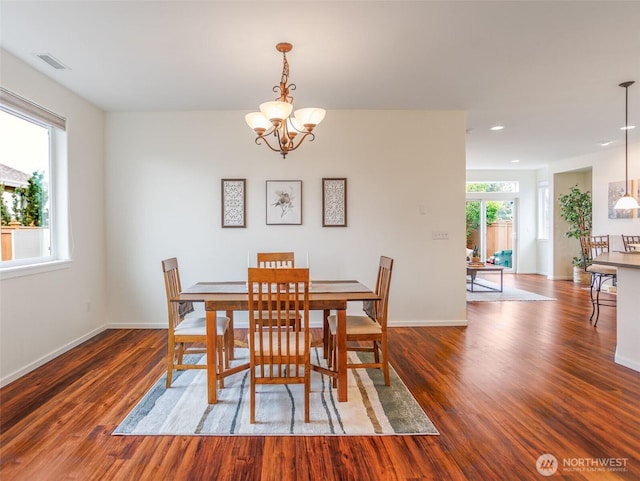 dining room with visible vents, a notable chandelier, baseboards, and wood finished floors