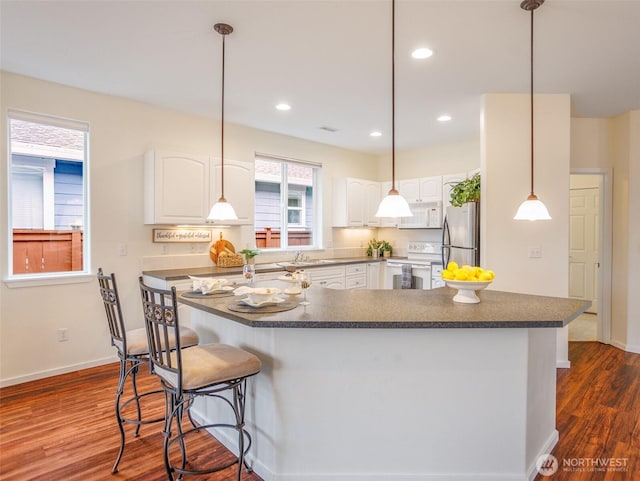 kitchen featuring dark countertops, white appliances, and white cabinetry