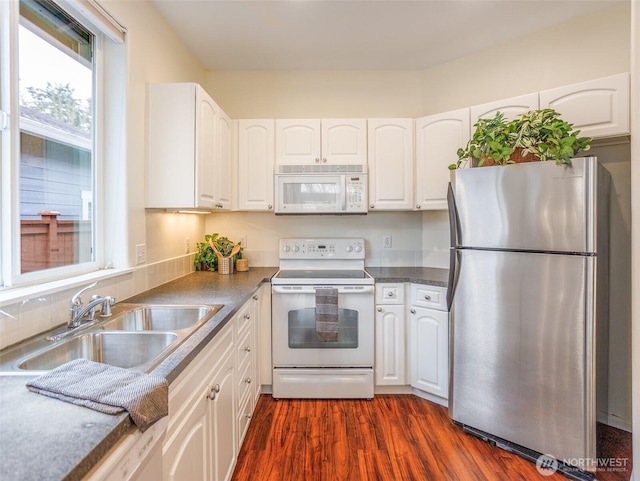 kitchen with white appliances, dark wood-style floors, white cabinets, and a sink