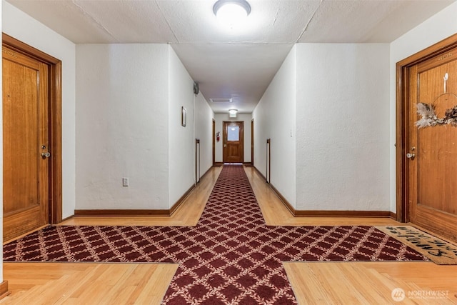 hallway with visible vents and baseboards