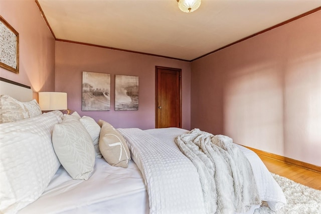 bedroom with ornamental molding, wood finished floors, and baseboards