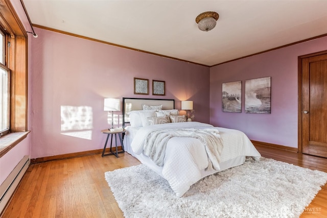 bedroom featuring light wood-style floors, baseboards, a baseboard heating unit, and ornamental molding