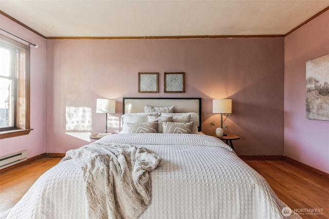 bedroom with baseboards, a baseboard heating unit, wood finished floors, and crown molding