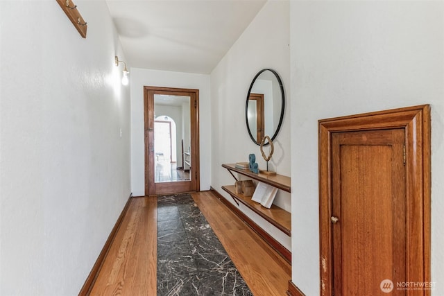 doorway with baseboards and wood finished floors