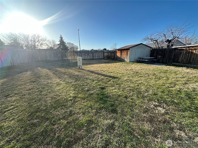 view of yard with a fenced backyard, a shed, and an outbuilding