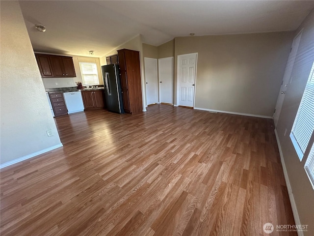 kitchen with stainless steel refrigerator with ice dispenser, lofted ceiling, open floor plan, white dishwasher, and wood finished floors