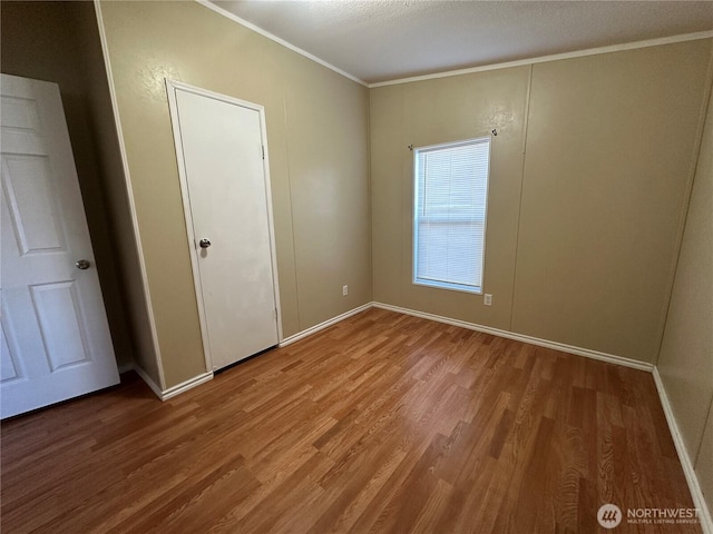 interior space with ornamental molding, baseboards, and wood finished floors