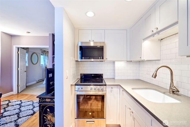 kitchen featuring tasteful backsplash, light countertops, appliances with stainless steel finishes, white cabinets, and a sink