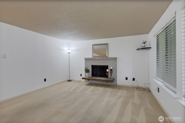 unfurnished living room with a textured ceiling, a fireplace, light carpet, and baseboards