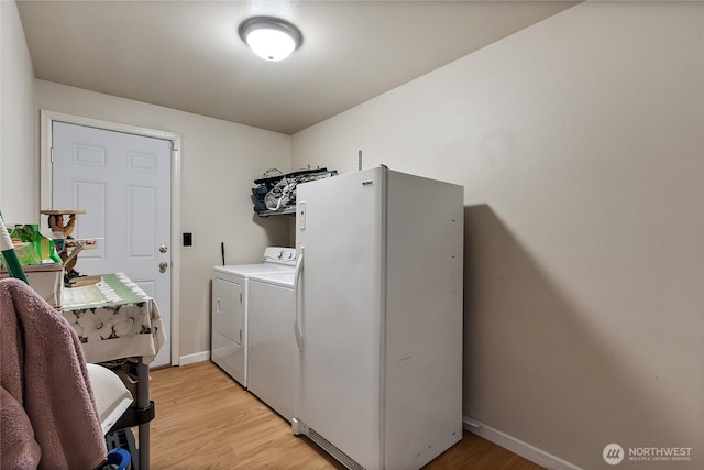 laundry area with light wood-type flooring, laundry area, washer and clothes dryer, and baseboards