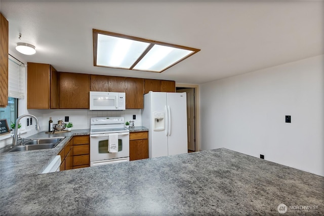 kitchen with white appliances, brown cabinetry, and a sink