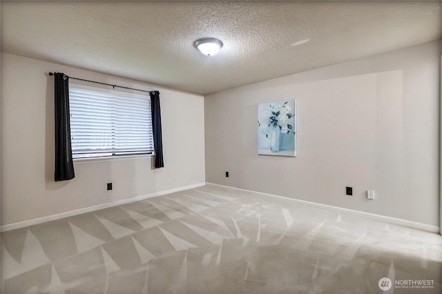 spare room with baseboards, a textured ceiling, and light colored carpet