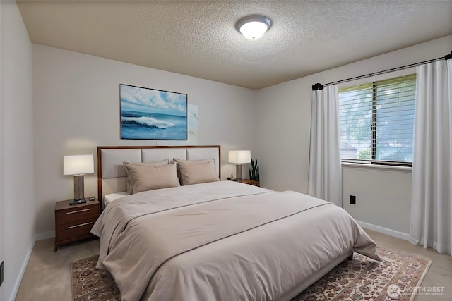 bedroom with light colored carpet, a textured ceiling, and baseboards