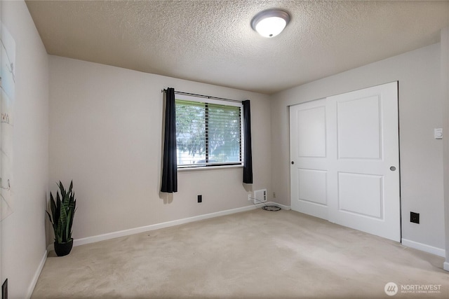 unfurnished bedroom featuring a textured ceiling, carpet floors, a closet, and baseboards