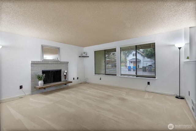 unfurnished living room with carpet floors, a brick fireplace, and a textured ceiling