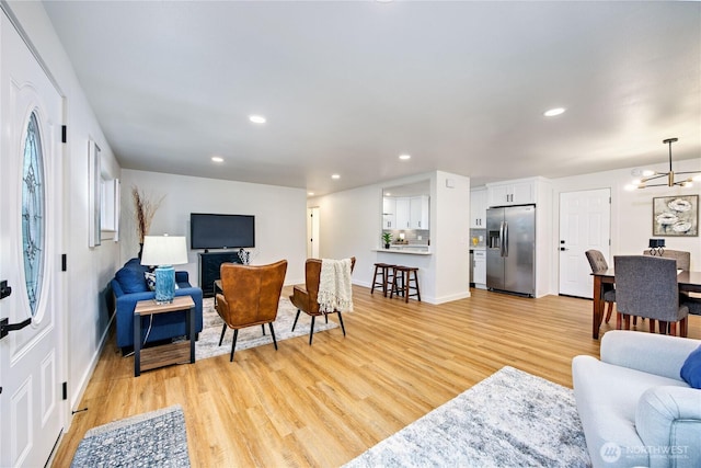 living area featuring recessed lighting, baseboards, a notable chandelier, and light wood finished floors