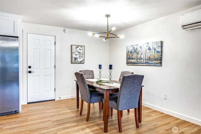 dining room with a chandelier, light wood finished floors, a wall mounted air conditioner, and baseboards