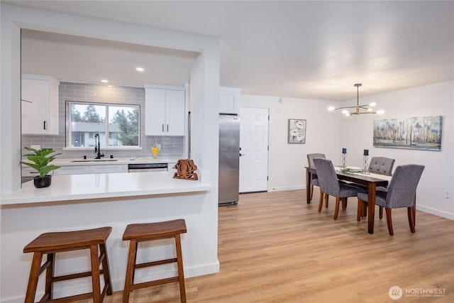 kitchen featuring tasteful backsplash, appliances with stainless steel finishes, a breakfast bar area, light countertops, and a sink