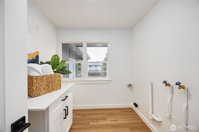 washroom with light wood finished floors, cabinet space, and baseboards