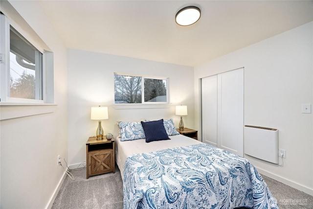 bedroom with radiator heating unit, a closet, carpet flooring, and baseboards