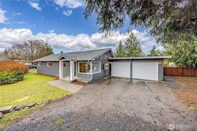 view of front of house with a garage, aphalt driveway, a front lawn, and fence