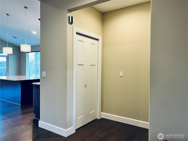 corridor with dark wood-style floors and baseboards