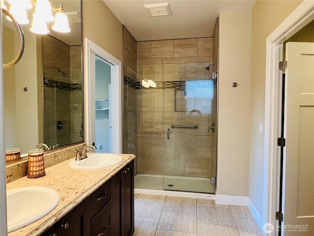 full bathroom with a sink, baseboards, a stall shower, and double vanity