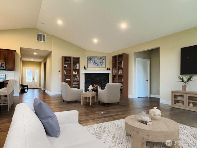 living area with visible vents, wood finished floors, baseboards, a fireplace, and lofted ceiling