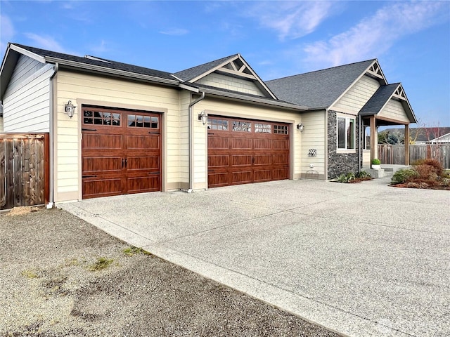 view of front facade featuring an attached garage, concrete driveway, and fence