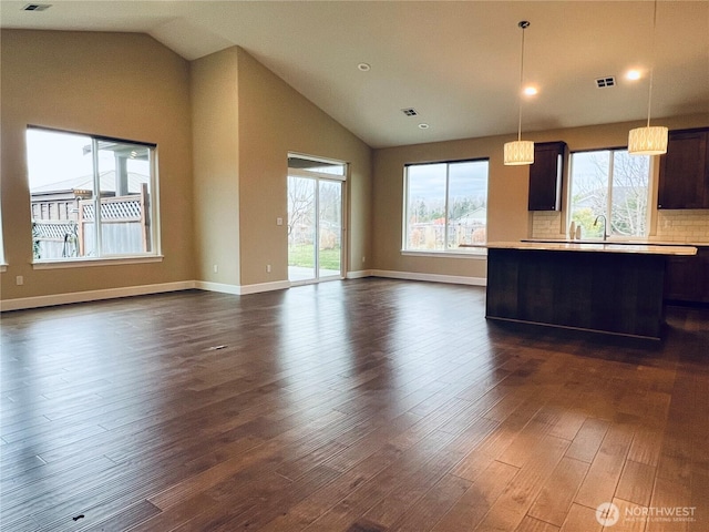 kitchen featuring visible vents, open floor plan, light countertops, lofted ceiling, and dark wood-style flooring