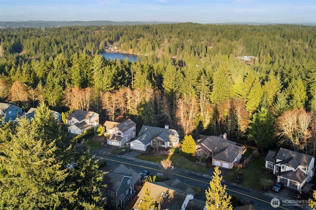 drone / aerial view with a residential view, a water view, and a wooded view