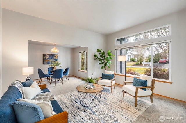 living area with a notable chandelier, plenty of natural light, carpet flooring, and baseboards