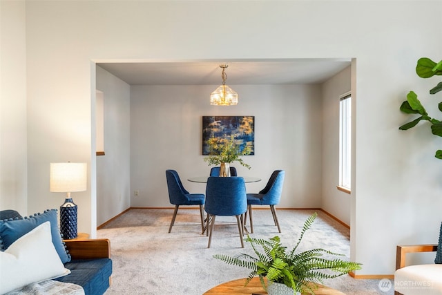 carpeted dining space featuring baseboards and a chandelier