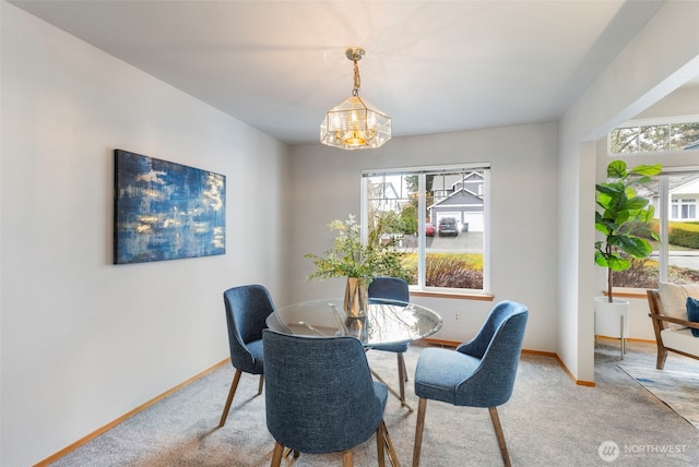 dining space featuring carpet flooring, baseboards, and an inviting chandelier